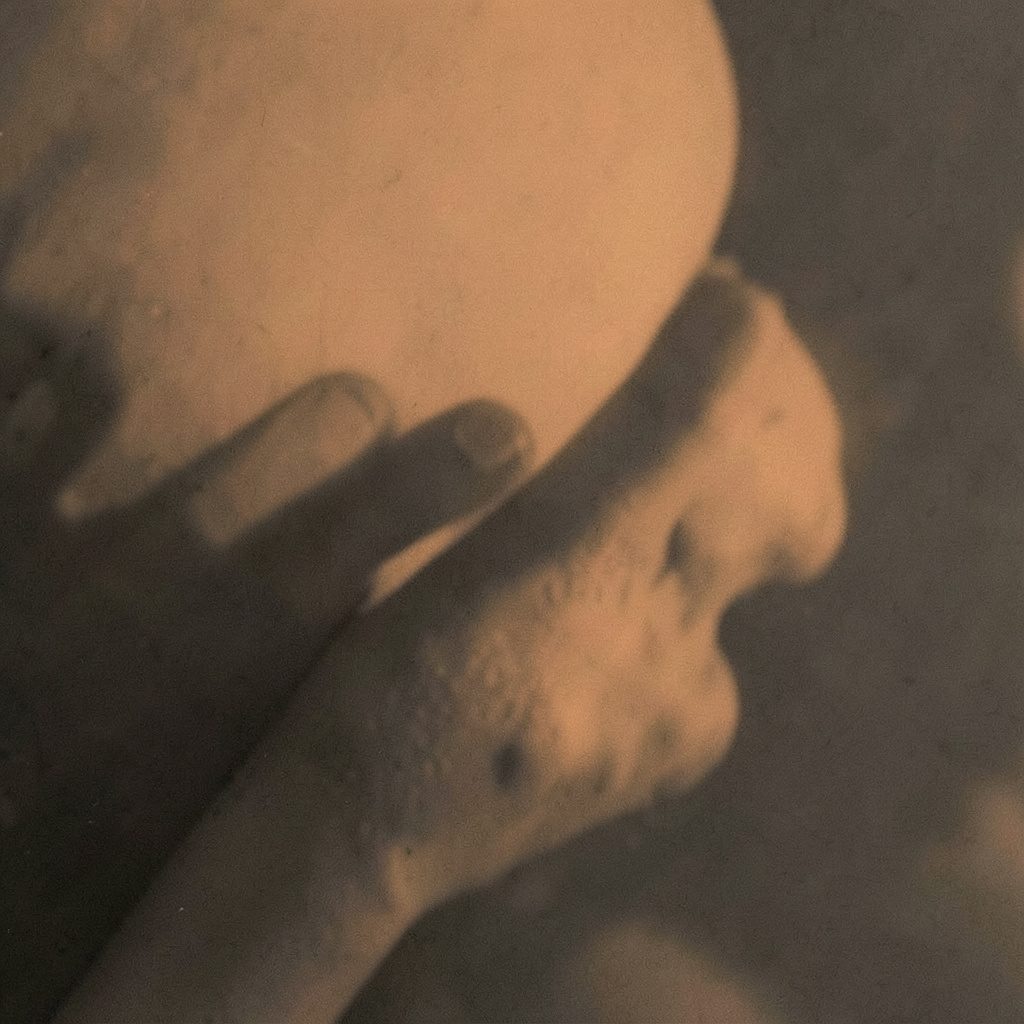 A dark duotone photograph of a digital screen with abstract video playback controls, rendered in deep charcoal and muted gold tones.